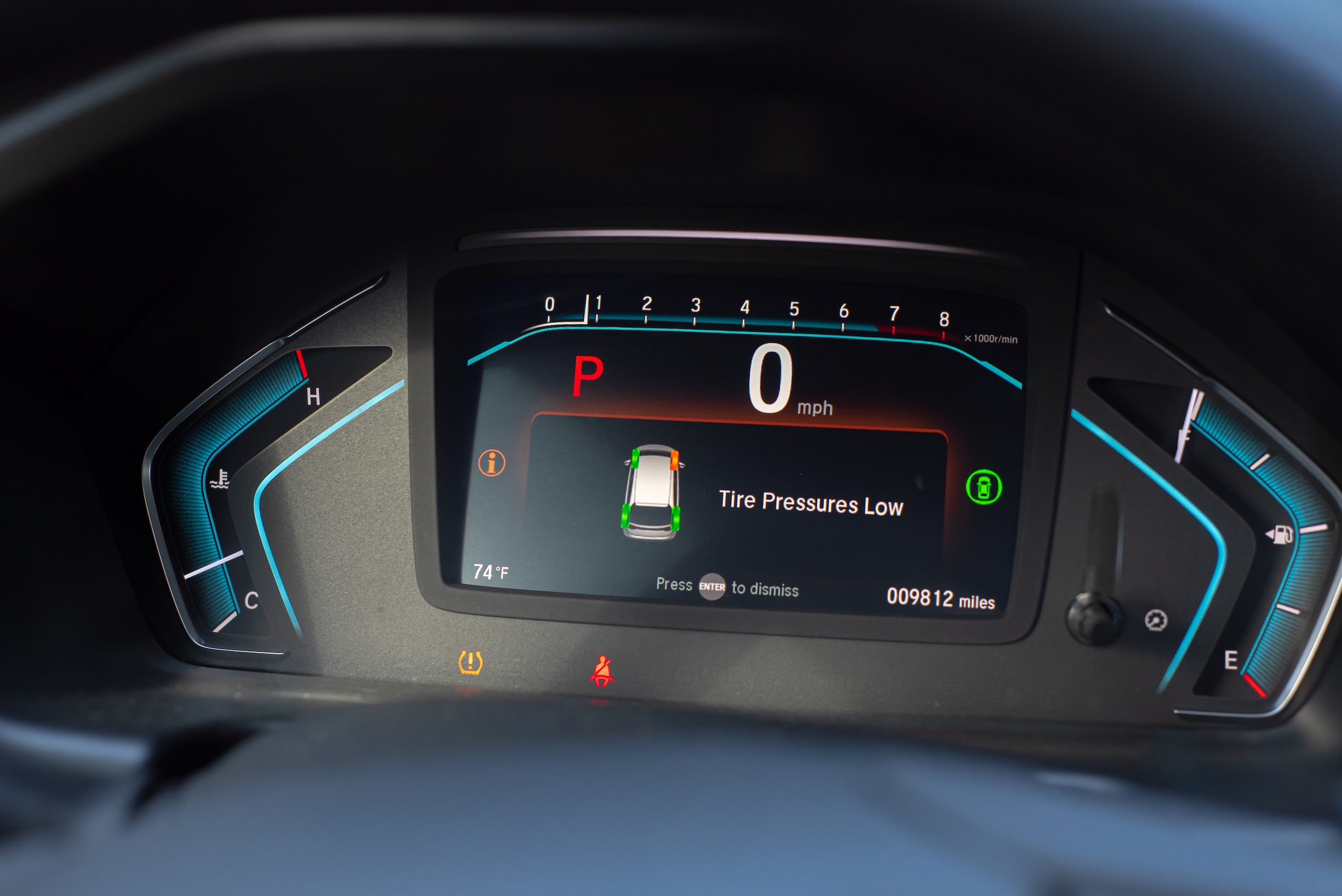 Close-up tire pressure low indicator displays on instrument panel of modern car in Parking mode, tire pressure monitoring system TPMS indicates lights on driver information interface