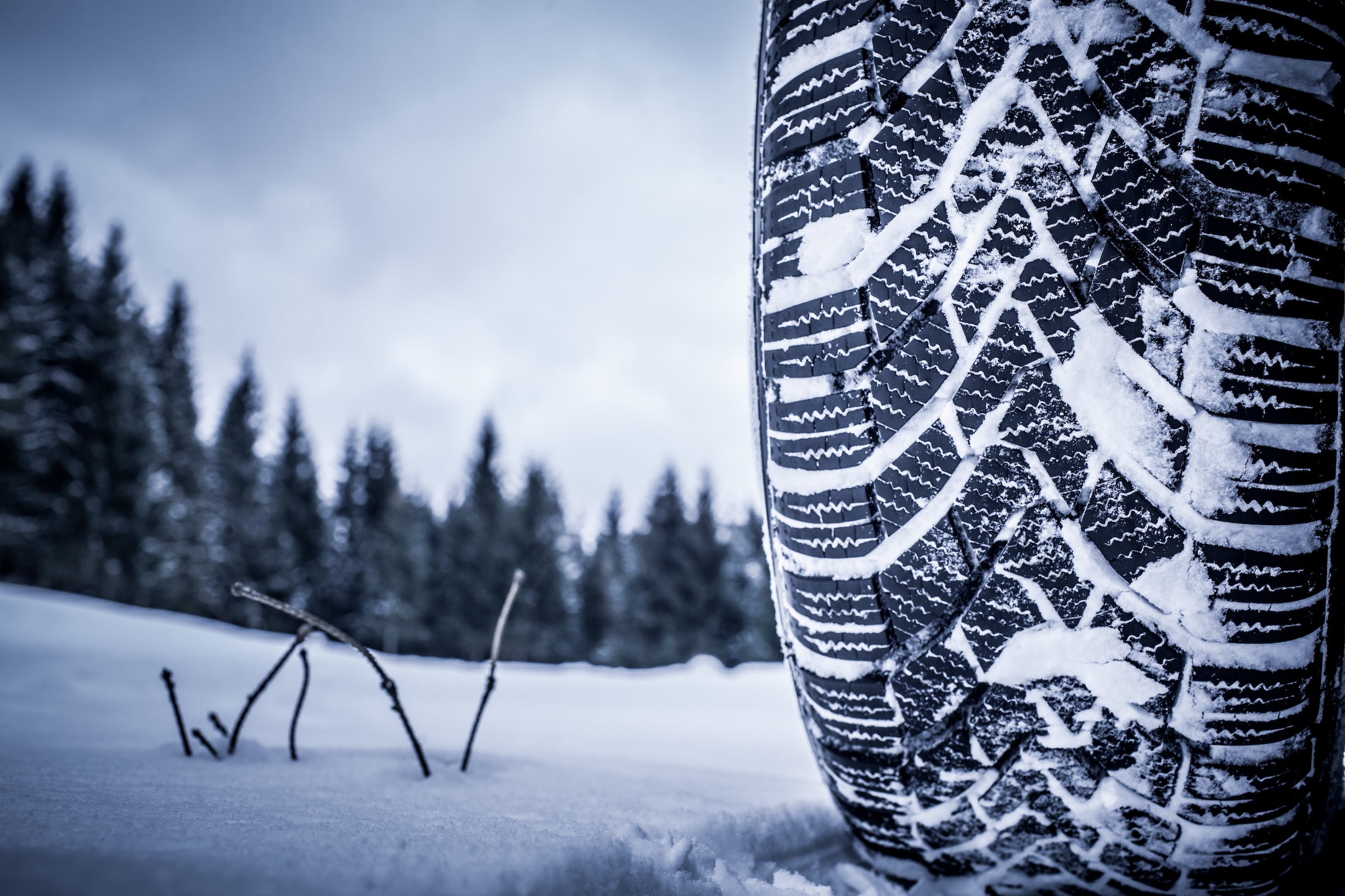 close up of winter tire driving through snow with snow in the specially designed tread.